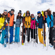 Gruppo di amici sorridenti sulla neve con sci e bastoncini
